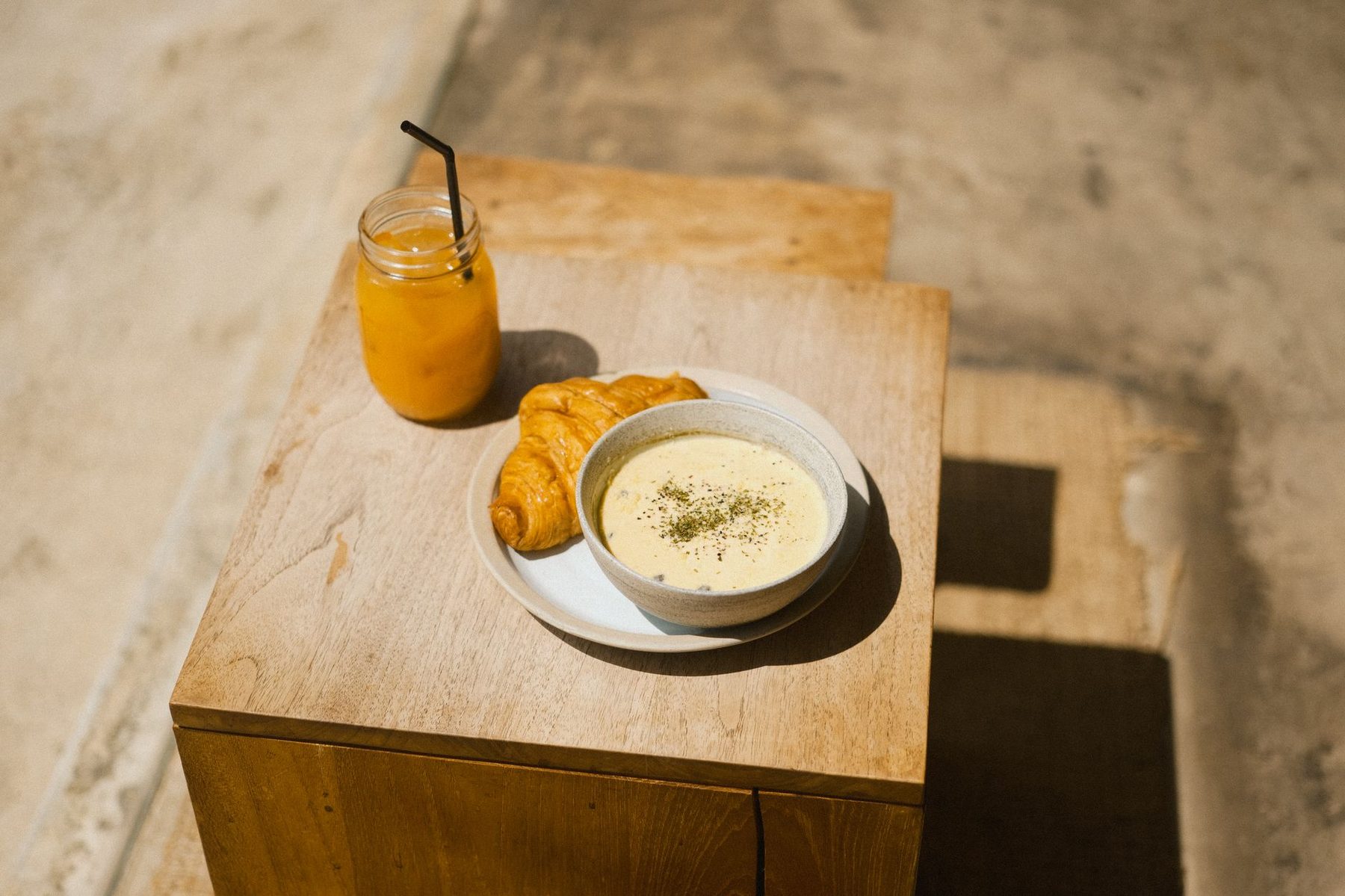 Petit-déjeuner posé sur un tabouret de bois contre le mur de pierre