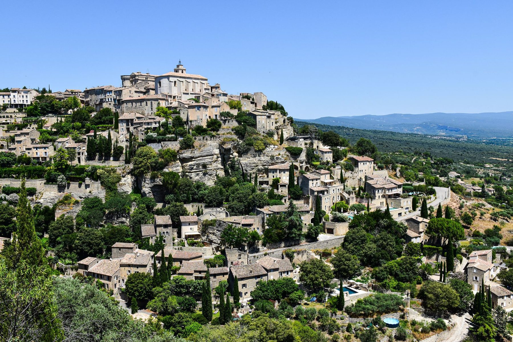 Le village de Gordes accroché à sa colline, vallée du Luberon en contrebas